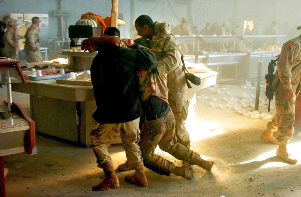 U.S. soldiers carry a wounded comrade moments after an insurgent suicide bombing on a dining facility during lunchtime on FOB Marez in Mosul, Iraq on Tuesday, Dec. 21, 2004.  22 people were killed in the blast.  (Richmond Times-Dispatch / Dean Hoffmeyer)