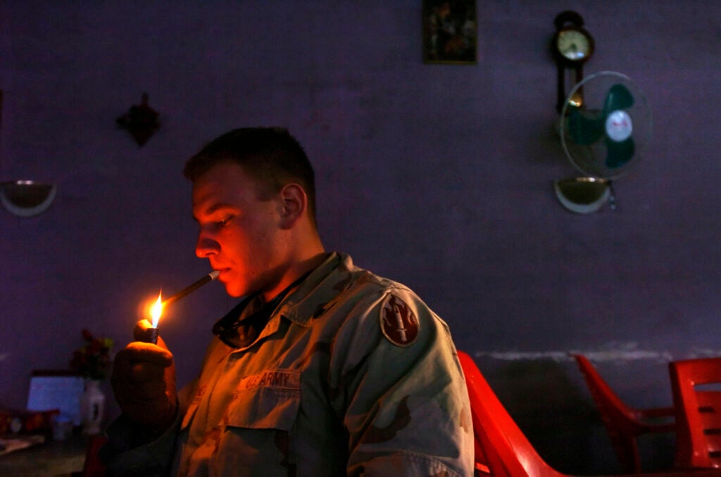 SPC Dimitri Borodouline, who was born in Leningrad, now St. Petersburg, Russia, and lives in Hollywood, Ca., lights a cigar in a coffee shop on Mosul Airfield, otherwise known as Diamondback, after electricity in the area went off on 12/19/04.  Borodouline is in the U.S. Army.