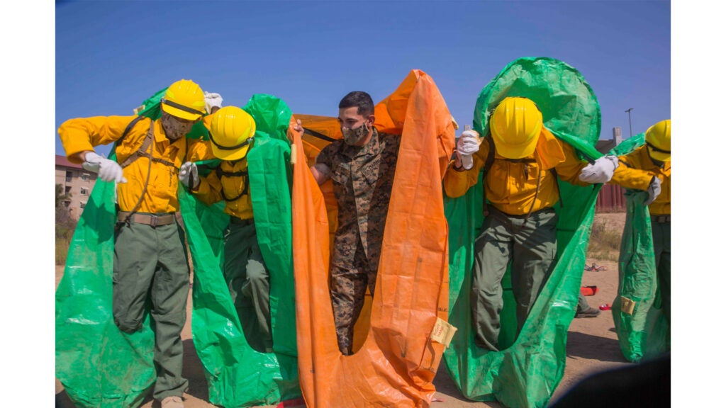 Marine Corps Cpl. Robert Rosa conducts training with a practice fire shelter at Marine Corps Base Camp Pendleton, Calif., Sept. 18, 2020. Marines and sailors assisted the U.S. Forest Service with fires in California. (Marine Corps photo / Lance Cpl. Ulises Salgado)