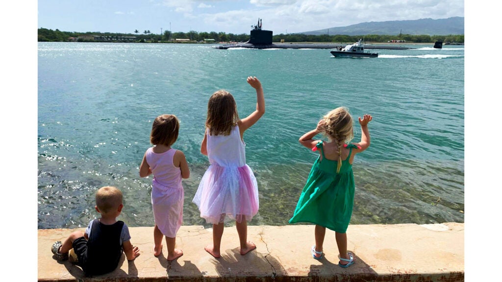 Children wave goodbye as the fast-attack submarine USS North Carolina departs for a regularly scheduled deployment at Joint Base Pearl Harbor-Hickam, Hawaii, March 25, 2020. (Navy photo / Chief Petty Officer Amanda Gray)