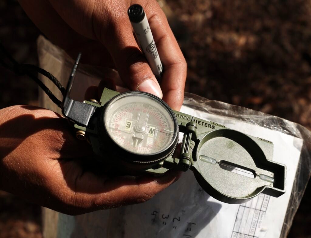 A recruit with Charlie Company, 1st Recruit Training Battalion, uses a lensatic compass while searching for location points during land navigation aboard Marine Corps Recruit Depot Parris Island, S.C., March 17, 2020. The Land Navigation Course requires recruits to navigate through unfamiliar territory using a lensatic compass, map, and protractor to find a specific objective. (U.S. Marine Corps photos by Lance Cpl. Samuel Fletcher)