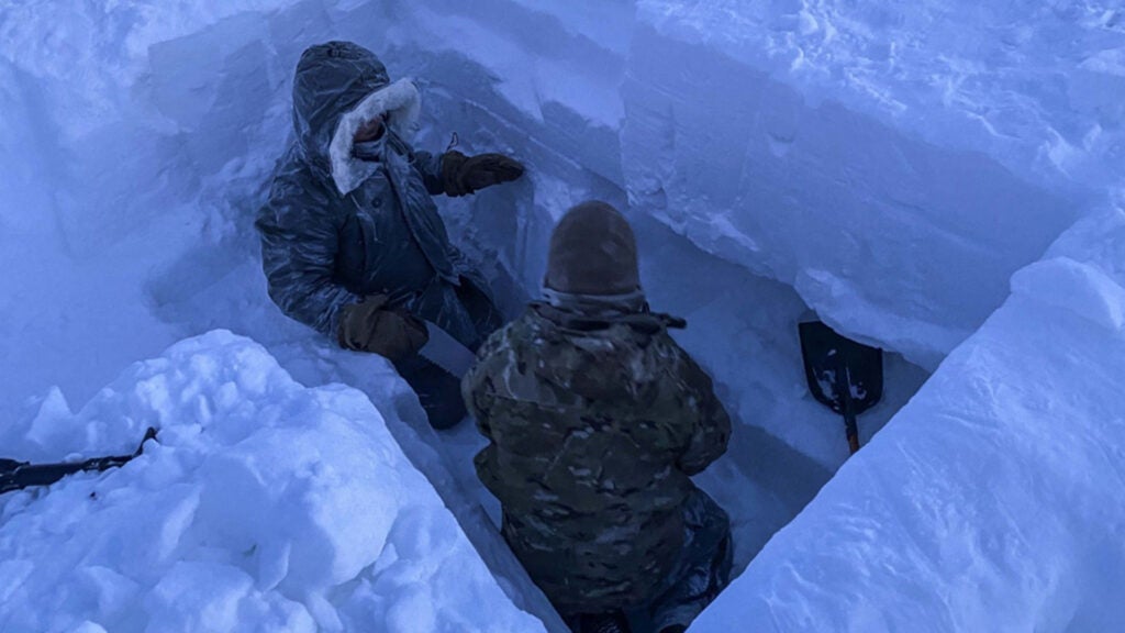 Survival, evasion, resistance and escape (SERE) specialists dig a snow cave at Utqiaġvik (Barrow), Alaska, Jan. 12, 2021. The snow caves served as shelter for the SERE specialists during their second night of upgrade training. It can comfortably house a maximum of 3 individuals. (Air Force photo / Master Sgt. Ryan M. Dewey)