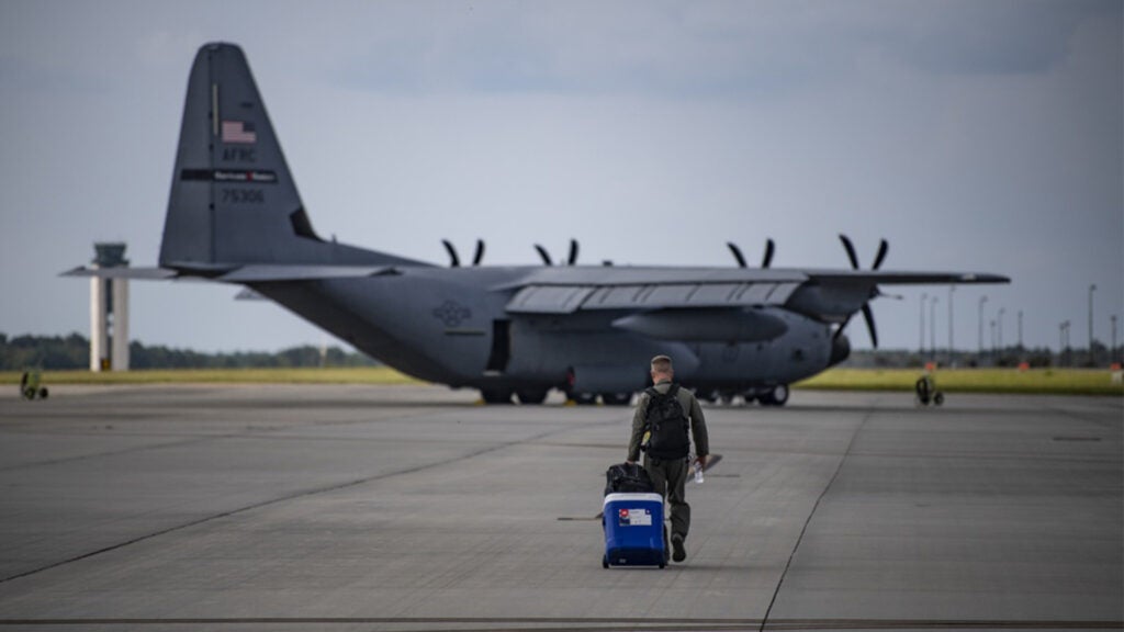 An Air Force reserve officer attached to the 53rd Weather Reconnaissance Squadron carries his gear and food for his next Hurricane Hunters mission into hurricane Florence, Sep. 11, 2018 out of the Savanah Air National Guard base, Georgia. The cooler of food is necessary because most of the foights are on average 10 hours long. (Air Force Photo by Technical Sgt. Chris Hibben)