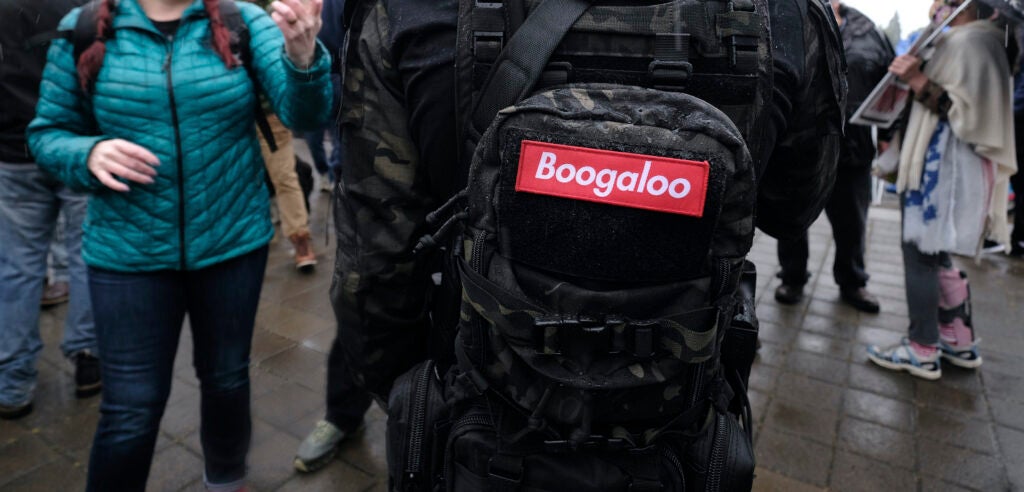A patch reads "Boogaloo" on the bag of a armed protester as people demonstrate at the capitol in Salem, Ore., on May 2, 2020. Governor Kate Brown announced a plan yesterday that could see some parts of the state reopen by May 15. (Photo by Alex Milan Tracy/Sipa USA)(Sipa via AP Images)