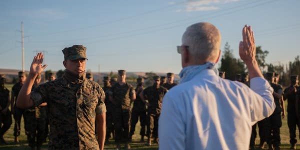 Former Defense Secretary Jim Mattis raises his knife hand to reenlist a lucky Marine corporal