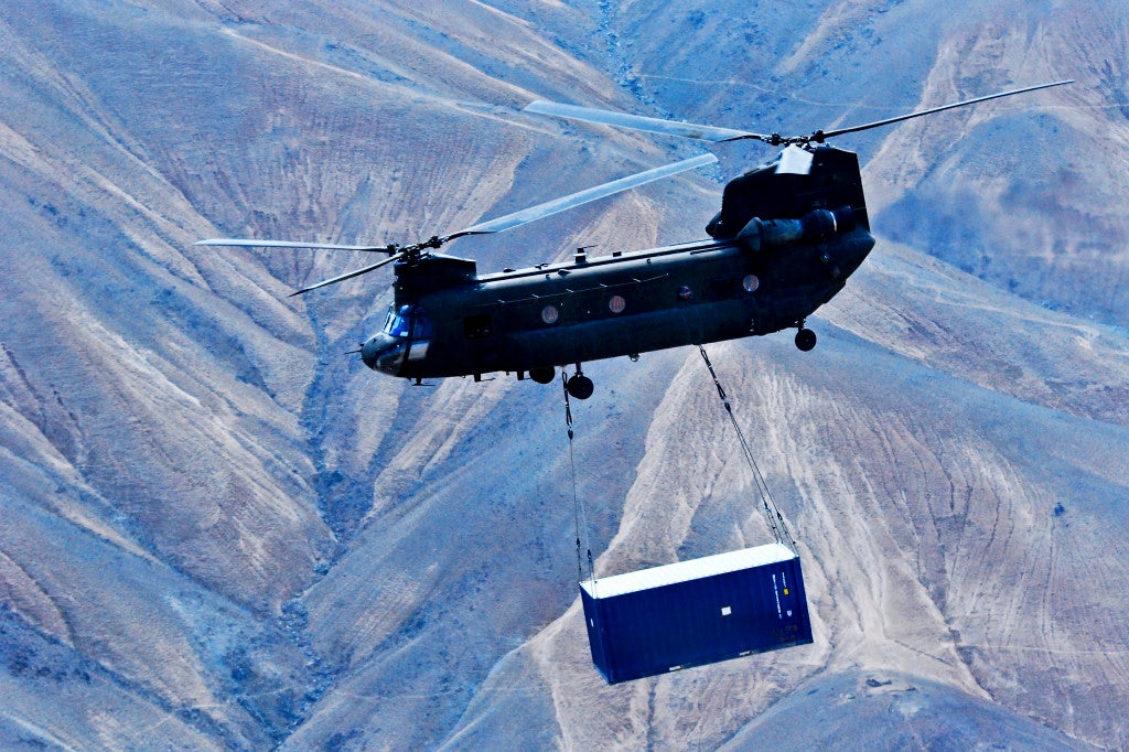 A U.S. Army CH-47 Chinook helicopter assigned to the 10th Combat Aviation Brigade and operated by Soldiers with Texas and Oklahoma Army National Guard units carries a sling-loaded shipping container during retrograde operations and base closures in Wardak province, Afghanistan, Oct. 26, 2013. (U.S. Army photo by Capt. Peter Smedberg/Released)