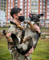 Cpl. Dustin Borchardt, a military dog handler with the 100th Military Police Detachment based out of Stuttgart, Germany, picks up his military working dog after she performed a bite suit demonstration in Ferizaj/Ferizaje, Kosovo, on Dec. 8, 2020 (Army National Guard photo / Staff Sgt. Tawny Schmit)