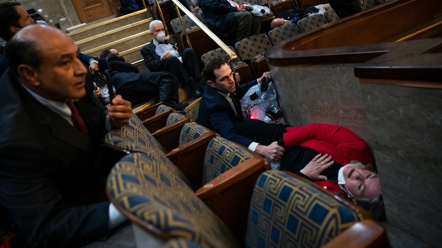 Rep. Jason Crow, D-Colo., comforts Rep. Susan Wild, D-Pa., while taking cover as protesters disrupt the joint session of Congress to certify the Electoral College vote on Wednesday, January 6, 2021.