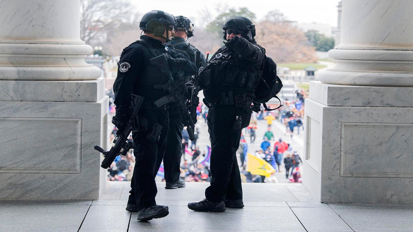 UNITED STATES - JANUARY 6: Capitol Police officers stand guard over rioters on the East Front before some broke into the Capitol to disrupt the joint session of Congress to certify the Electoral College vote on Wednesday, January 6, 2021. (Photo By Tom Williams/CQ Roll Call via AP Images)