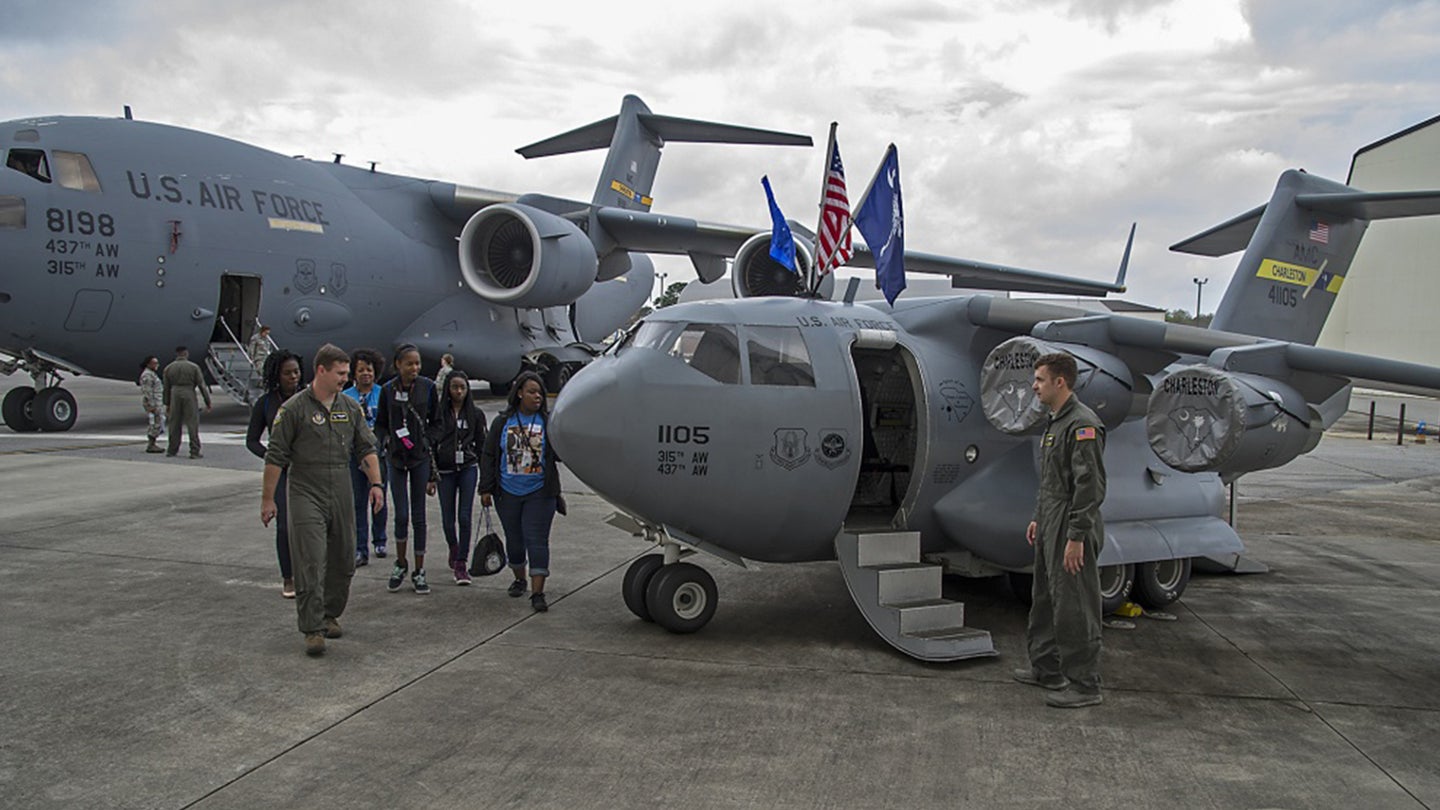 Staff Sgt. James Bradley, 317th Airlift Squadron loadmaster, leads a group of girls to the mini C-17 Globemaster there where Staff Sgt. Austin Dove, 317th AS loadmaster, waits during the 11th Annual Joint Base Charleston Women in Aviation Career Day here, March 20.(Air Force photo / Michael Dukes)