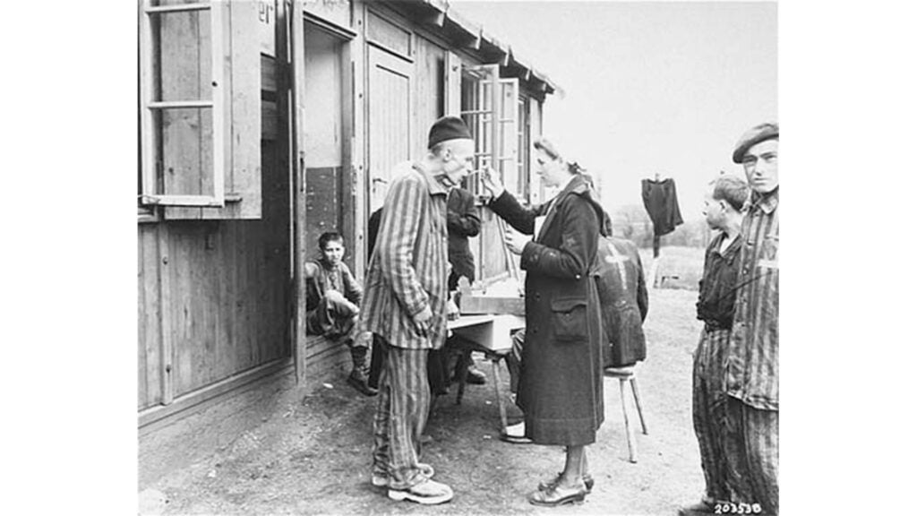 A sick Polis survivor in the Hannover-Ahlem  sub-camp received medicine from a German Red Cross worker, April 11, 1945 (U.S. Holocaust Memorial Museum photo)