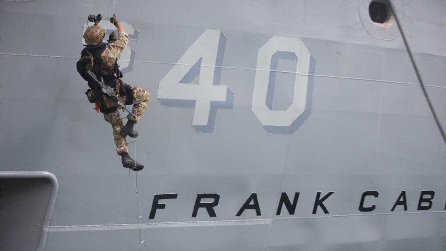 A British Royal Marine climbs an insertion ladder during a simulated raid aboard the submarine tender USS Frank Cable (AS 40) March 27, 2018, in Guam (Marine Corps photo / Sgt. Carl King)