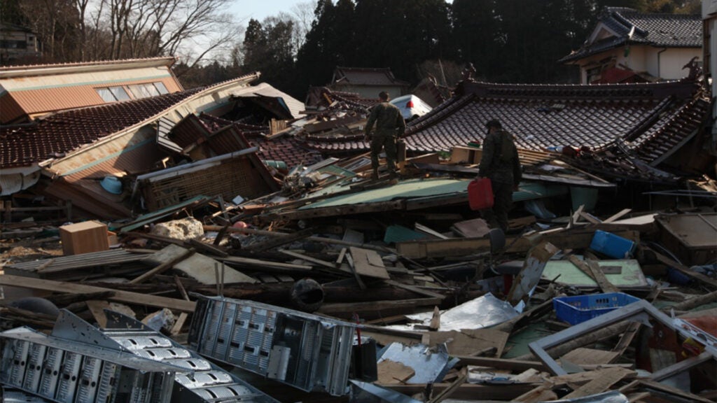 April 1, 2011, U.S. Marines with 2nd Battalion, 5th Marine Regiment, Battalion Landing Team (BLT), 31st Marine Expeditionary Unit (MEU), walk over rubble and debris during a humanitarian assistance/disaster relief mission at Uranohama Port, Oshima Island, Japan, in support of Operation Tomodachi. (Marine Corps photo / Lance Cpl. Brennan O'Lowney)