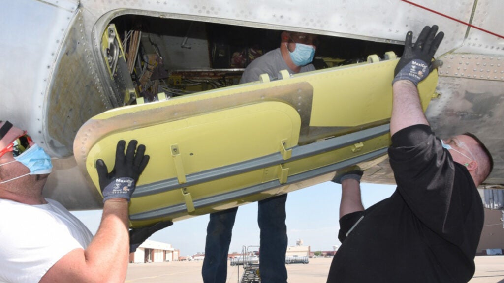 Daniel Geyer, Corey Roundtree and Avrome Sullivan, 565th Aircraft Maintenance Squadron, replace the lower hatches on "Wise Guy" as part of programmed depot maintenance at Tinker Air Force Base Oklahoma, April 21, 2020. (U.S. Air Force photo/Kelly White)