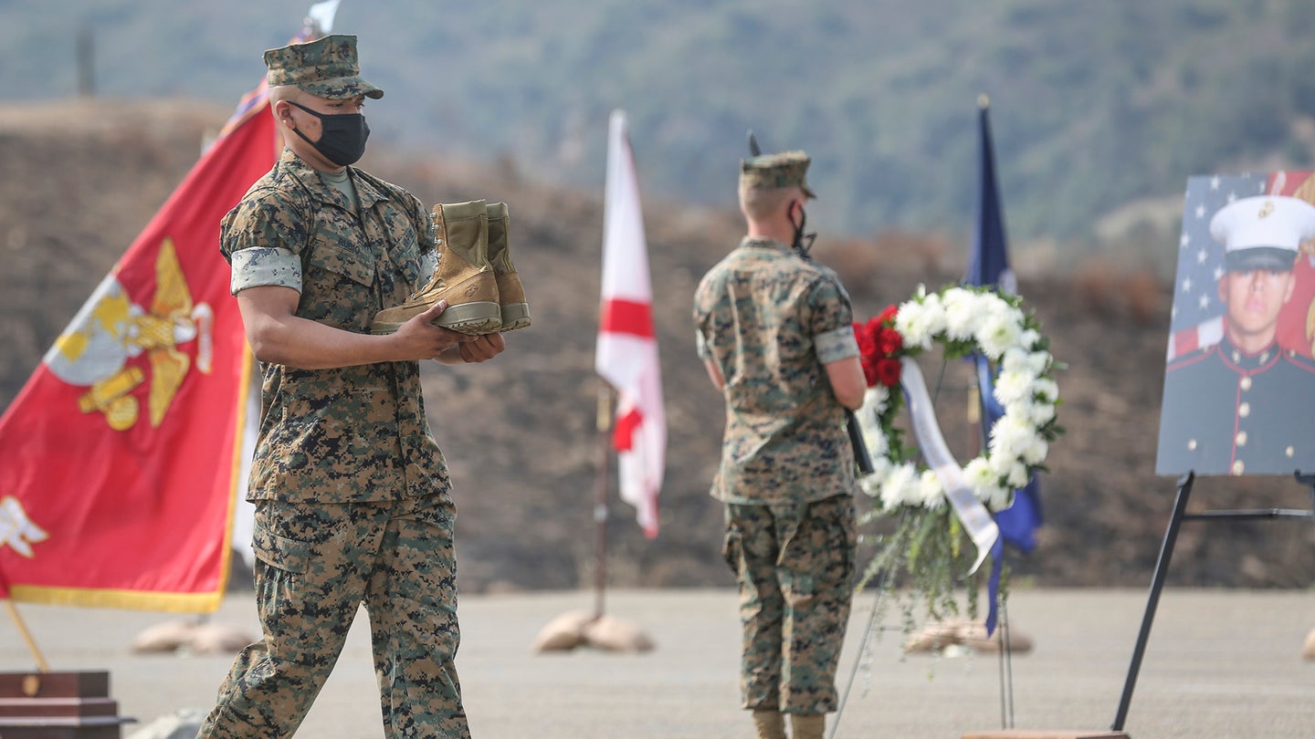 A U.S. Marine with Battalion Landing Team 1/4, 15th Marine Expeditionary Unit, carries a pair of combat boots during a memorial service at Marine Corps Base Camp Pendleton, California, Aug. 21, 2020. The service was held in remembrance of the eight Marines and one Sailor from Bravo Company, BLT 1/4, 15th MEU, who died in an assault amphibious vehicle mishap off the coast of San Clemente Island, California, July 30. (U.S. Marine Corps photo by Cpl. Dalton S. Swanbeck)