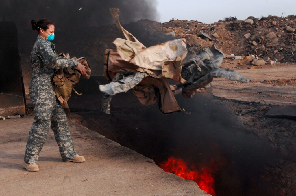 Senior Airman Frances Gavalis, 332nd Expeditionary Logistics Readiness Squadron equipment manager, tosses unserviceable uniform items into a burn pit, March 10. Military uniform items turned in must be burned to ensure they cannot be used by opposing forces. Airman Gavalis is deployed from Kirtland Air Force Base, N.M.