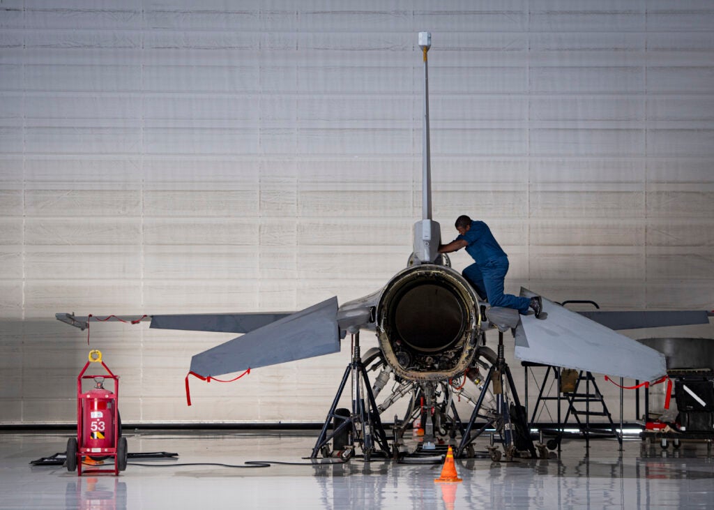 A maintainer works to convert an F-16 into a Thunderbird aerial demonstration jet at Nellis Air Force Base. (Air Force photo)