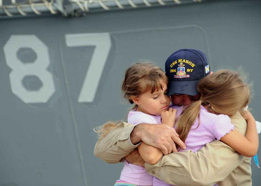 Chief Petty Officer Joseph Stevenson hugs his daughters goodbye before he deploys aboard the guided-missile destroyer USS Mason. The Mason is deploying as part of the Theodore Roosevelt Carrier Strike Group supporting maritime security operations and theater security cooperation efforts in the U.S. 5th and 6th Fleet areas of responsibility.