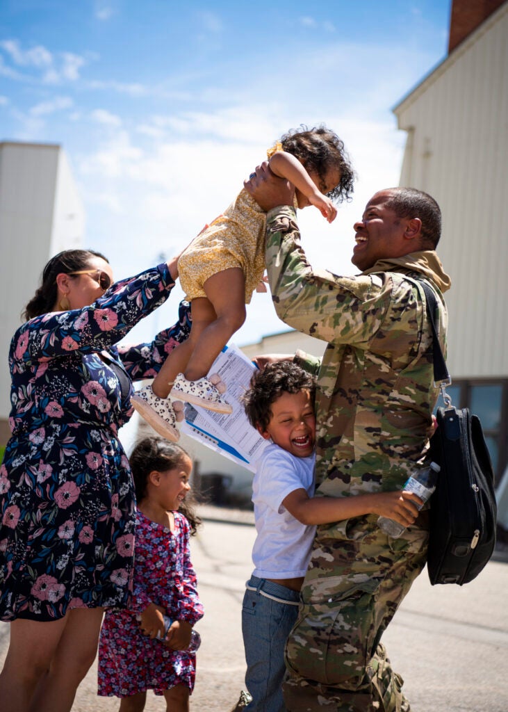 A U.S. Air Force Airman from 389th Fighter Squadron embraces his family after returning from a deployment, June 3, 2020, at Mountain Home Air Force Base, Idaho. The deployment was extended by two months due to COVID-19, resulting in the Airmen being away from home for eight months. (U.S. Air Force photo by Airman 1st Class Andrew Kobialka)