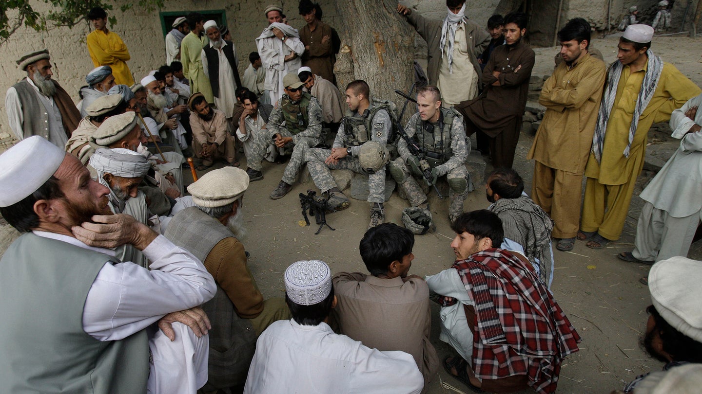 In this Nov. 3, 2009, file photo, Lt. Thomas Goodman, center, of the 2nd Battalion, 12th Infantry Regiment, 4th Brigade Combat Team, 4th Infantry Division meets with villagers in Qatar Kala in the Pech Valley of Afghanistan's Kunar province with his interpreter Ayazudin Hilal, center left with hat. (AP Photo/David Guttenfelder, File)