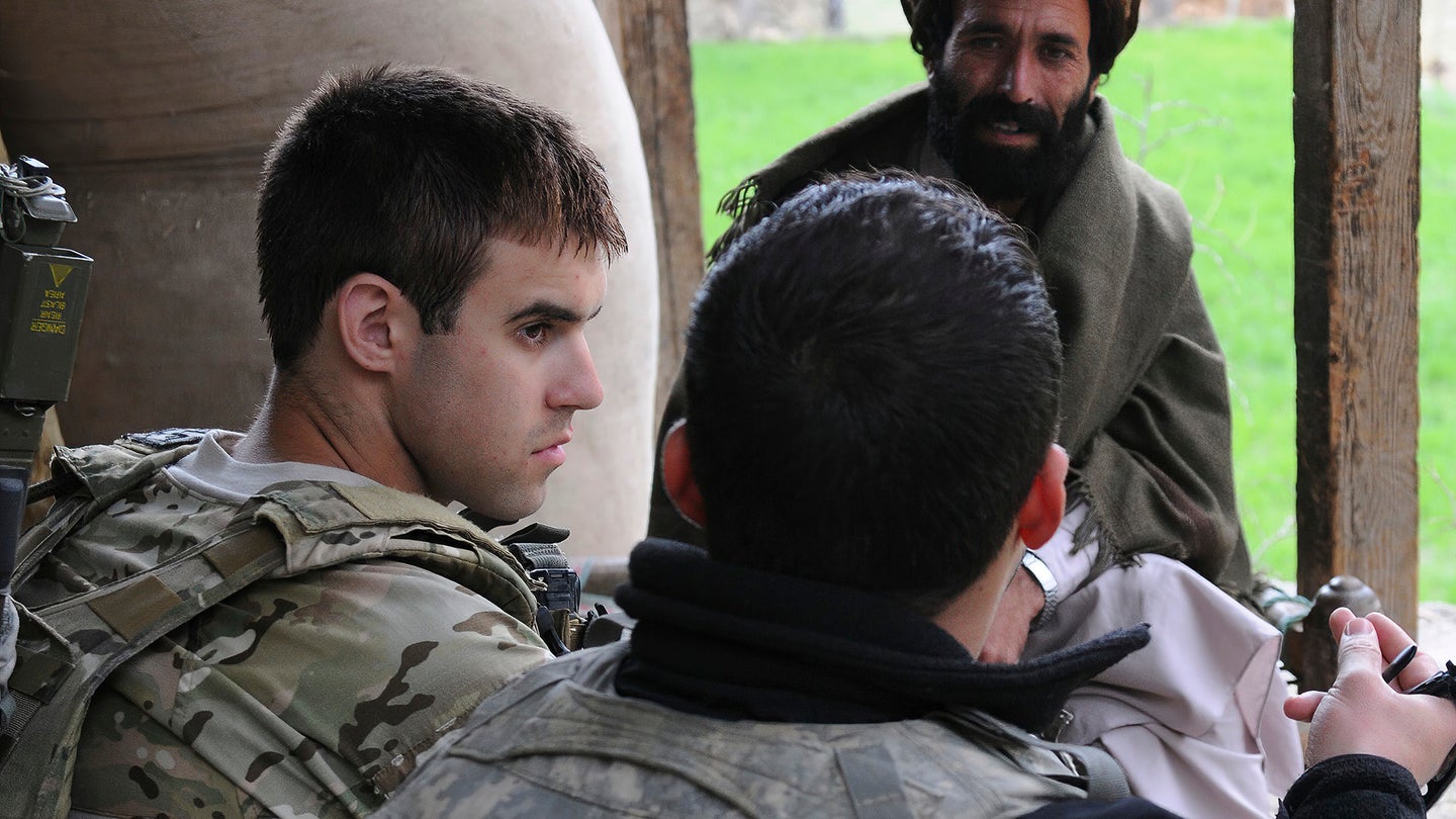 Army 1st Lt. Thomas J. Goodman, the platoon leader of 3rd Platoon, Chosen Company, 2nd Battalion, 12th Infantry Regiment, listens to his interpreter Ayazudin Hilal, back to camera, during a visit to Kunar province. (Staff Sgt. Gary A. Witte/U.S. Army via AP)
