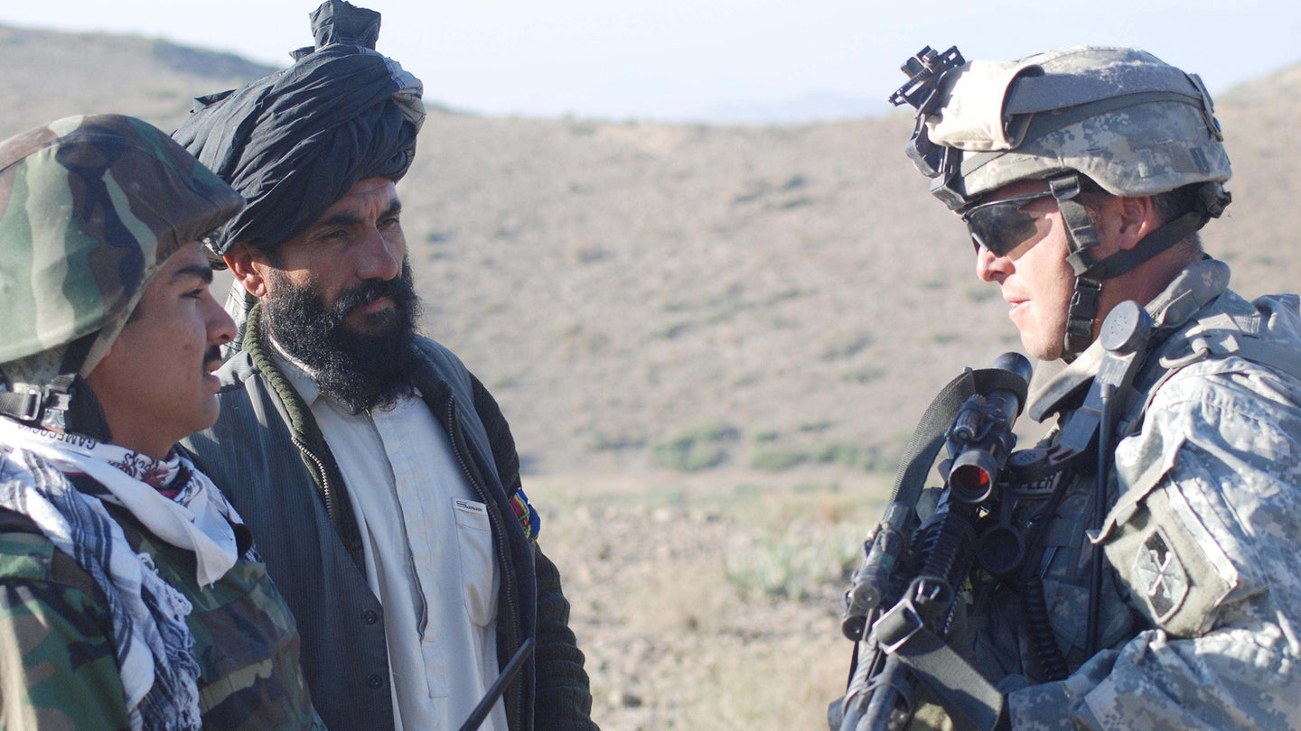 Afghan Border Police mentor, Army 1st Lt. Robin C. Crumpler, right, from Beulaville, N.C., questions an Afghan man, center, through an interpreter during a recent security patrol in Khowst Province, Afghanistan.