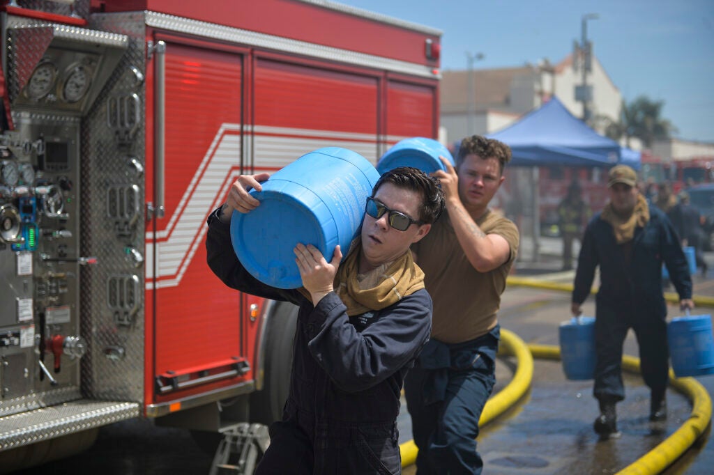 2007-N-MJ716-0046 SAN DIEGO (July 12, 2020) - U.S. Navy Sailors carry barrels of aqueous film forming foam (AFFF) in support of putting out a fire on board USS Bonhomme Richard (LHD 6) at Naval Base San Diego, July 12. On the morning of July 12, a fire was called away aboard the ship while it was moored pier side at Naval Base San Diego. Base and shipboard firefighters responded to the fire. USS Bonhomme Richard is going through a maintenance availability, which began in 2018. (U.S. Navy Photo by Mass Communication Specialist 2nd Class Austin Haist)