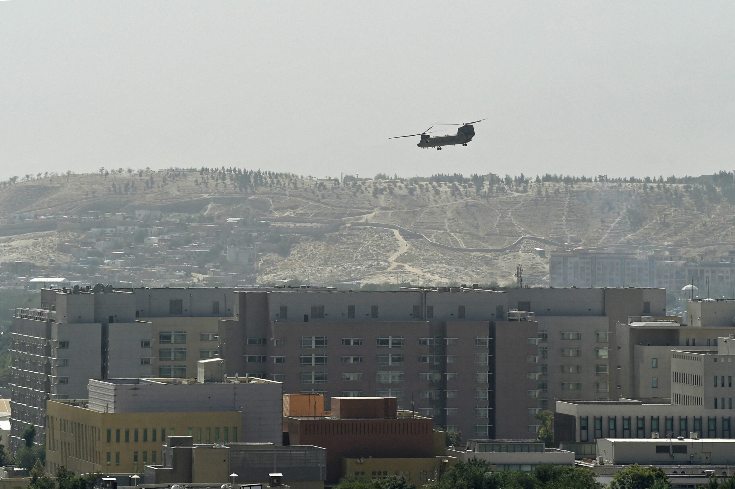 TOPSHOT - A U.S. Chinook military helicopter flies above the US embassy in Kabul on August 15, 2021. Several hundred employees of the US embassy in Kabul have been evacuated from Afghanistan, a US defense official said on August 15, 2021, as the Taliban entered the capital. (Photo by Wakil KOHSAR / AFP) (Photo by WAKIL KOHSAR/AFP via Getty Images)