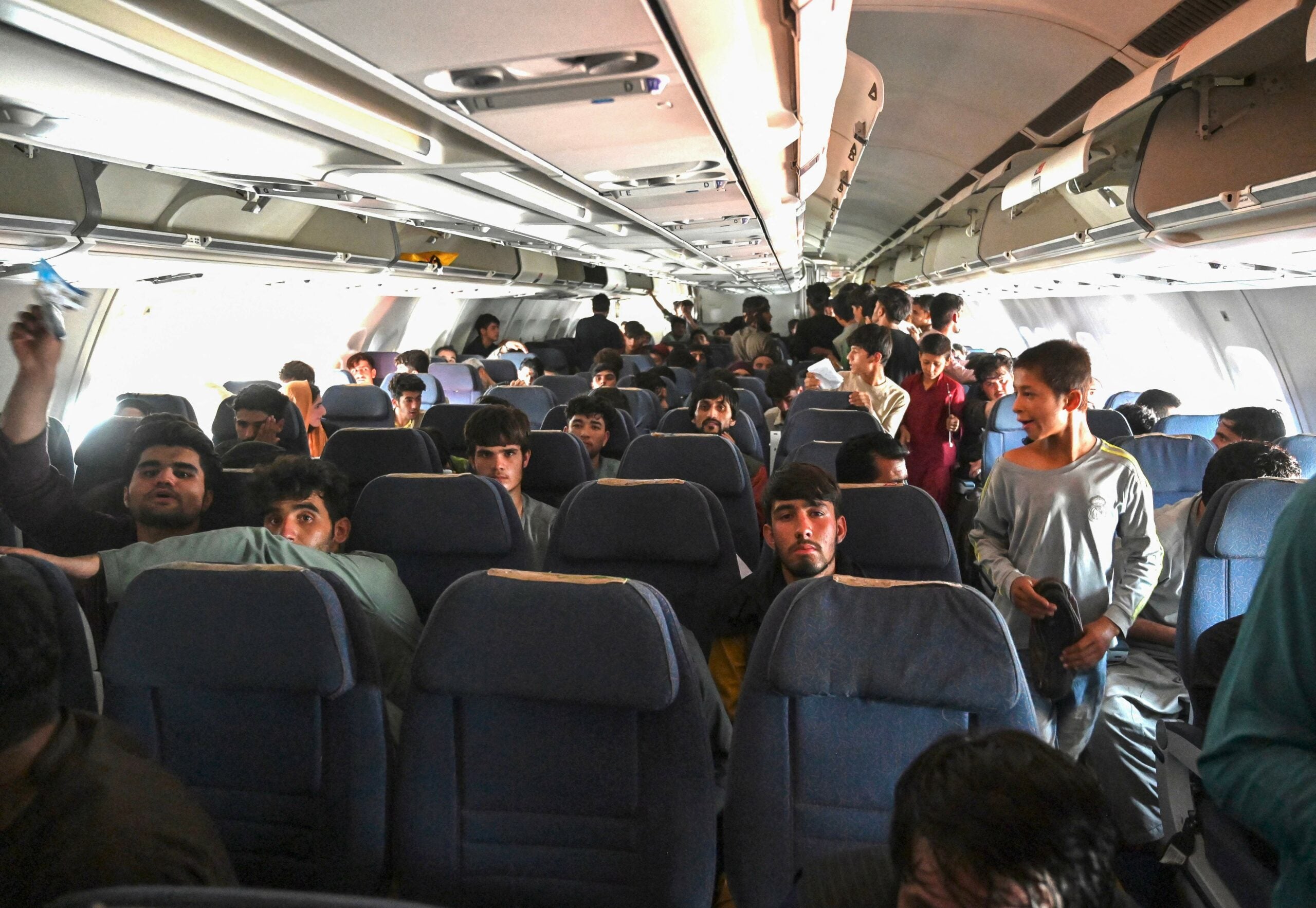TOPSHOT - Afghan passengers sit inside a plane as they wait to leave the Kabul airport in Kabul on August 16, 2021, after a stunningly swift end to Afghanistan's 20-year war, as thousands of people mobbed the city's airport trying to flee the group's feared hardline brand of Islamist rule. (Photo by Wakil Kohsar / AFP) (Photo by WAKIL KOHSAR/AFP via Getty Images)