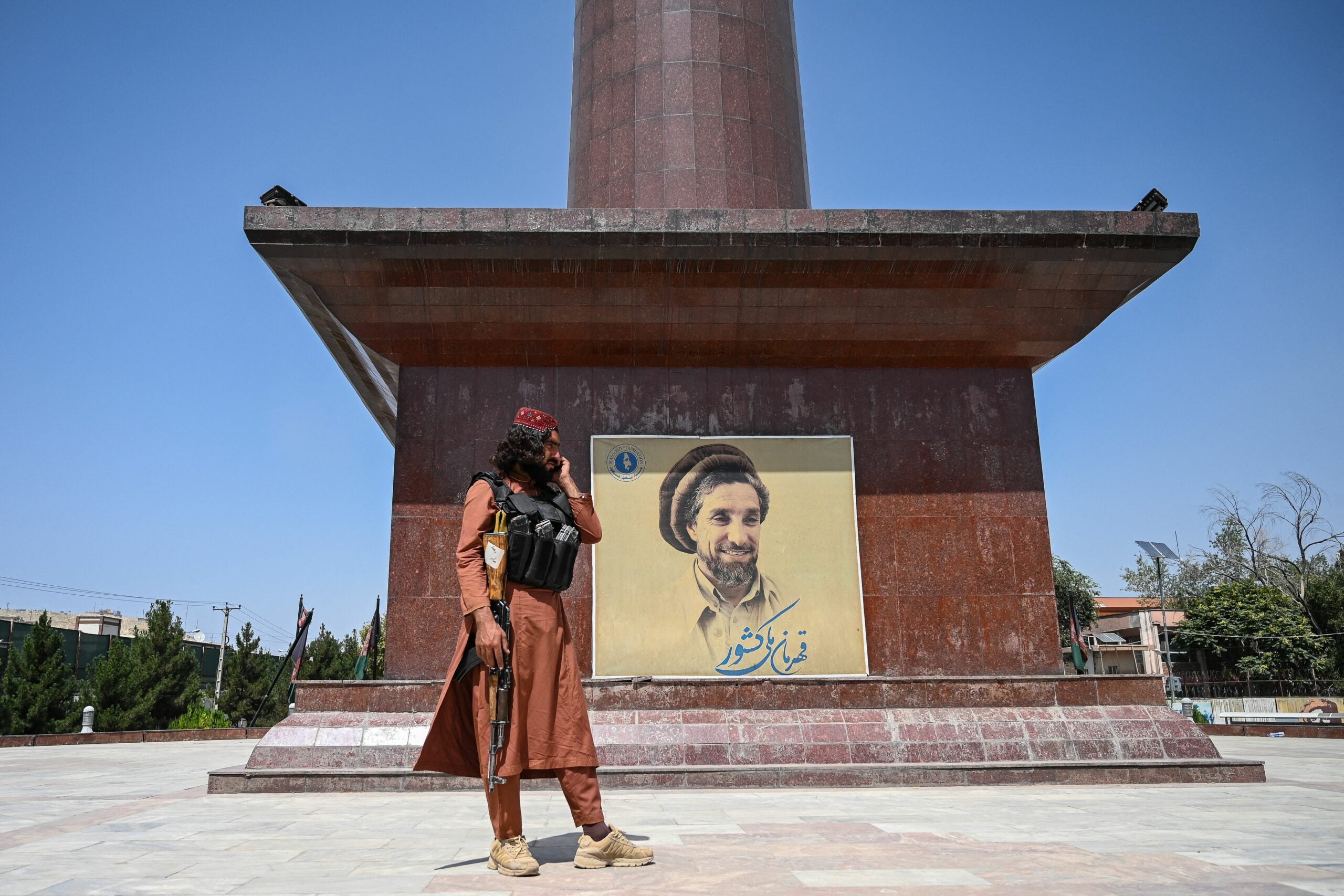 A Taliban fighter stand next to poster bearing the image late Afghan commander Ahmad Shah Massoud at the Massoud Square in Kabul on August 16, 2021. (Photo by Wakil Kohsar / AFP) (Photo by WAKIL KOHSAR/AFP via Getty Images)