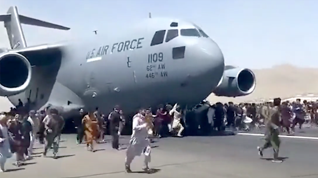 Afghans run alongside a C-17 Globemaster III transport aircraft at Hamid Karzai International Airport in Kabul on August 16, 2021.