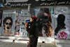 A Taliban fighter walks past a beauty saloon with images of women defaced using a spray paint in Shar-e-Naw in Kabul on August 18, 2021. (Photo by Wakil KOHSAR / AFP) (Photo by WAKIL KOHSAR/AFP via Getty Images)