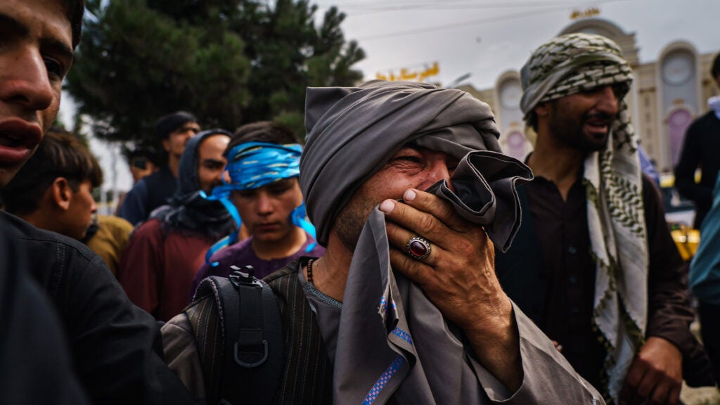 KABUL, AFGHANISTAN -- AUGUST 17, 2021: A man cries as he watches fellow Afghans get wounded after Taliban fighters use guns fire, whips, sticks and sharp objects to maintain crowd control over thousands of Afghans who continue to wait outside the Kabul Airport for a way out, on airport road in Kabul, Afghanistan, Tuesday, Aug. 17, 2021.  (MARCUS YAM / LOS ANGELES TIMES)