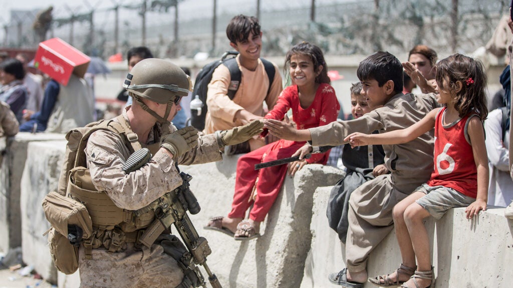 A Marine with Special Purpose Marine Air-Ground Task Force-Crisis Response-Central Command (SPMAGTF-CR-CC) plays with children waiting to process during an evacuation at Hamid Karzai International Airport, Kabul, Afghanistan, Aug. 20. U.S. service members are assisting the Department of State with an orderly drawdown of designated personnel in Afghanistan. (U.S. Marine Corps photo by Sgt. Samuel Ruiz).