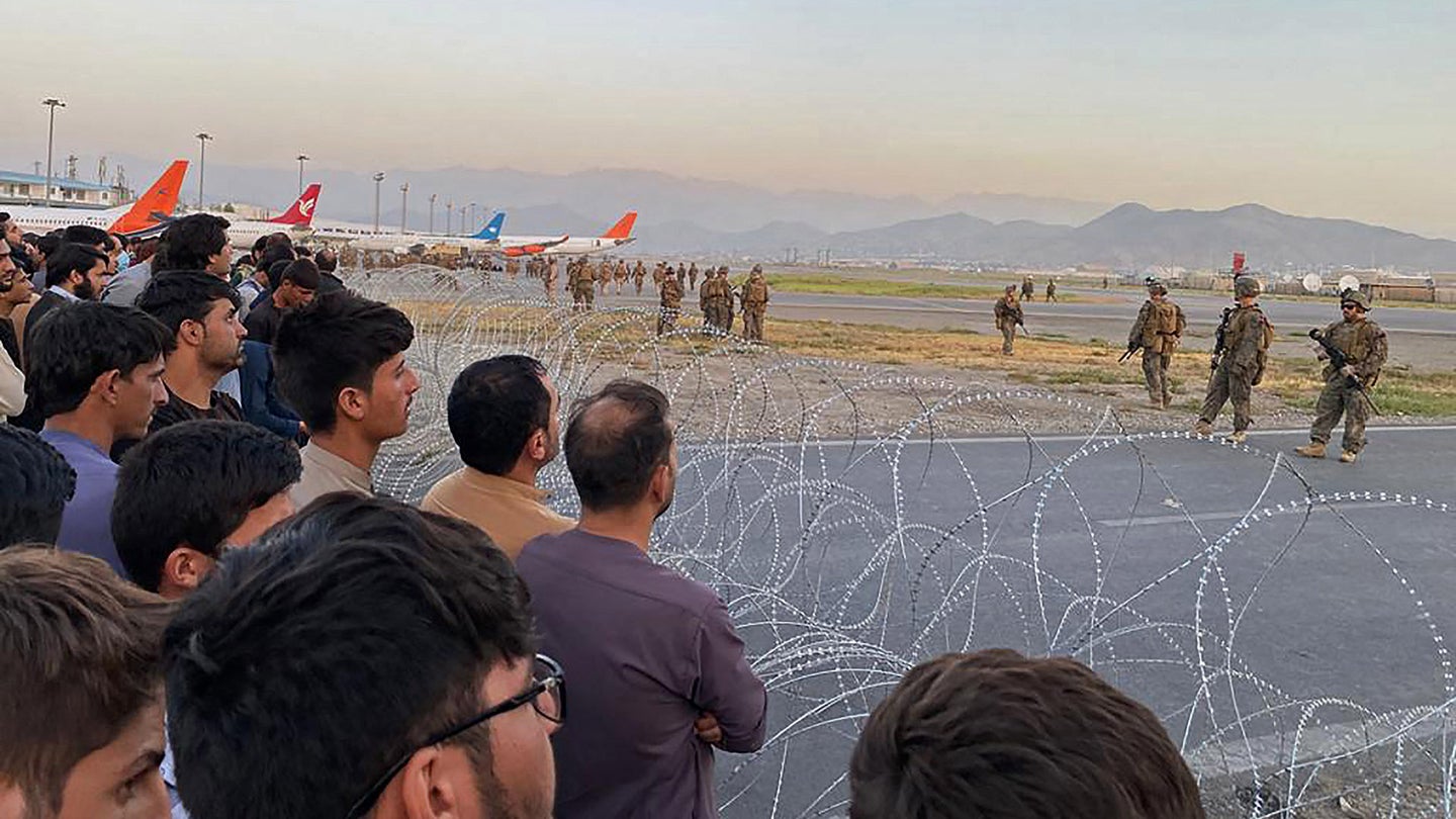 FILE PHOTO: Afghans crowd at the airport as US soldiers stand guard in Kabul on August 16, 2021. (Photo by Shakib Rahmani / AFP) (Photo by SHAKIB RAHMANI/AFP via Getty Images)