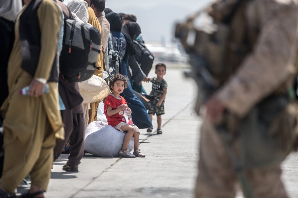 A child waits with her family to board a U.S. Air Force Boeing C-17 Globemaster III during an evacuation at Hamid Karzai International Airport, Kabul, Afghanistan, Aug. 22. U.S. service members are assisting the Department of State with an orderly drawdown of designated personnel in Afghanistan. (U.S. Marine Corps photo by Sgt. Samuel Ruiz).