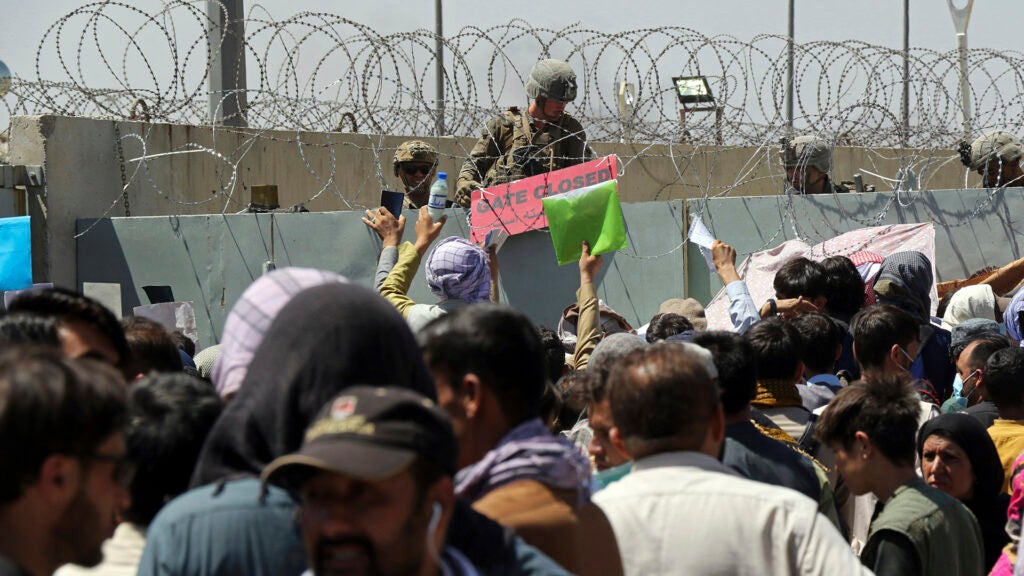 A U.S. soldier holds a sign indicating a gate is closed as hundreds of people gather some holding documents, near an evacuation control checkpoint on the perimeter of the Hamid Karzai International Airport, in Kabul, Afghanistan, Thursday, Aug. 26, 2021. (AP Photo/Wali Sabawoon)