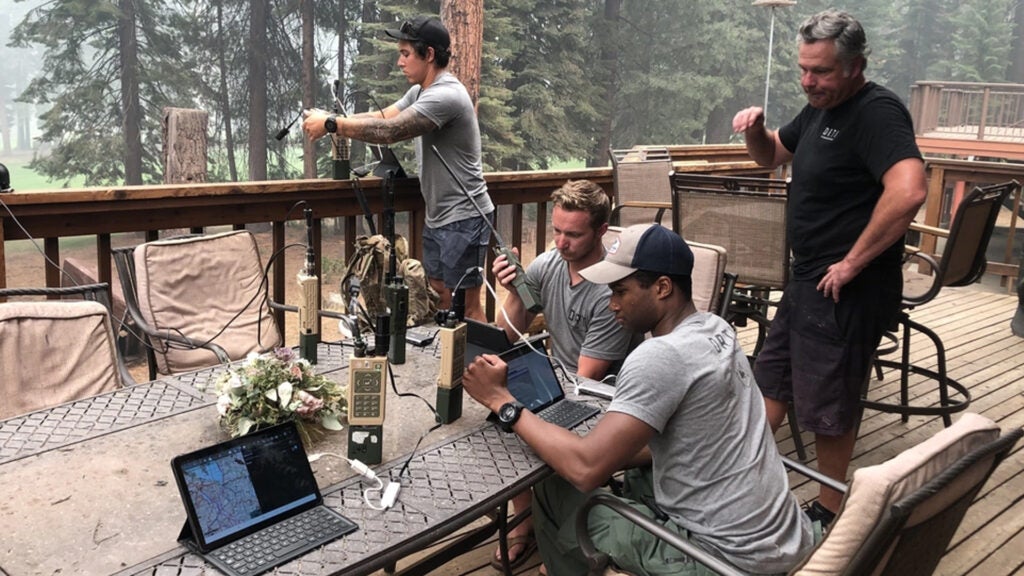 Members of the Pennsylvania Air National Guard are serving as imagery experts, providing live aerial video streaming to fire bosses working on the front lines of the devastating fires. Here they gather fire perimeter information from the RC26 on the DIXIE FIRE in Chester, Calif. July 25. Shown are: Senior Airman Julius Reed, Pennsylvania Air National Guard (front seated); Staff Sgt. William Gray, Pennsylvania Air National Guard (rear seated), Senior Airman Jesse Mauricio Oklahoma Air National Guard (standing by railing) and Mr. Joel Kerley (standing right), National Interagency Fire Center. (Air National Guard photo by Master Sgt. Brent Hill)