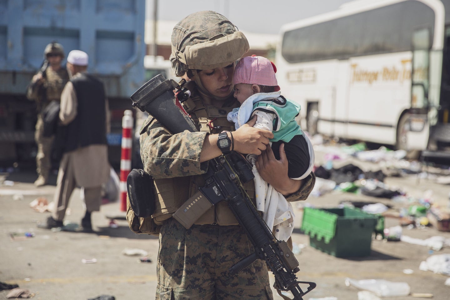 A U.S. Marine with the 24th Marine Expeditionary Unit (MEU) carries a baby as the familiy processes through the Evacuation Control Center (ECC) during an evacuation at Hamid Karzai International Airport, Kabul, Afghanistan, Aug. 28.