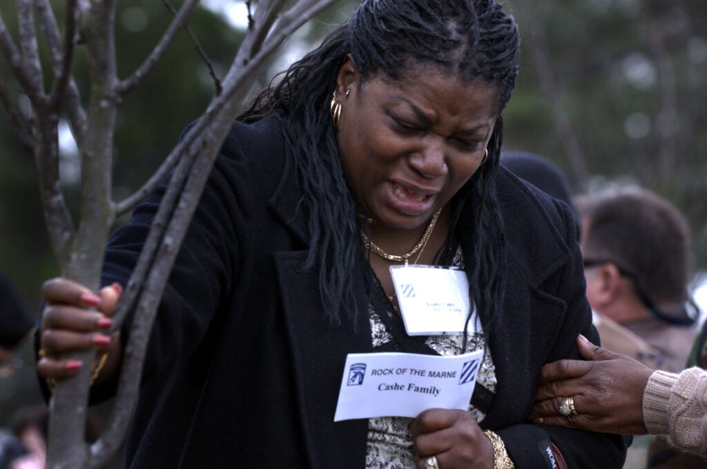 Kasinal Cashe prays Thursday Dec. 15, 2005 for her brother, U.S. Army Sgt. 1st Class Alwyn Cashe of Oviedo, Fla., while holding the eastern redbud tree planted in his name at Warriors' Walk in Fort Stewart, Ga. Cashe died in Iraq from wounds he suffered while rescuing other soldiers trapped inside a Bradley Fighting Vehicle that was destroyed by a roadside bomb. The tree dedication ceremony was the second largest for those killed in action while serving with the Army's 3rd Infantry Division. (AP Photo/Stephen Morton)