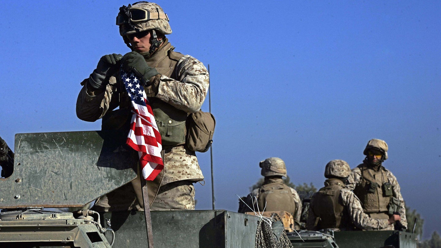 FILE PHOTO: A Marine hangs an American flag atop his Humvee during a sweep through the Zaidon market, located southeast of Fallujah, during an operation, 15 November, 2005.  (DAVID FURST/AFP via Getty Images.)