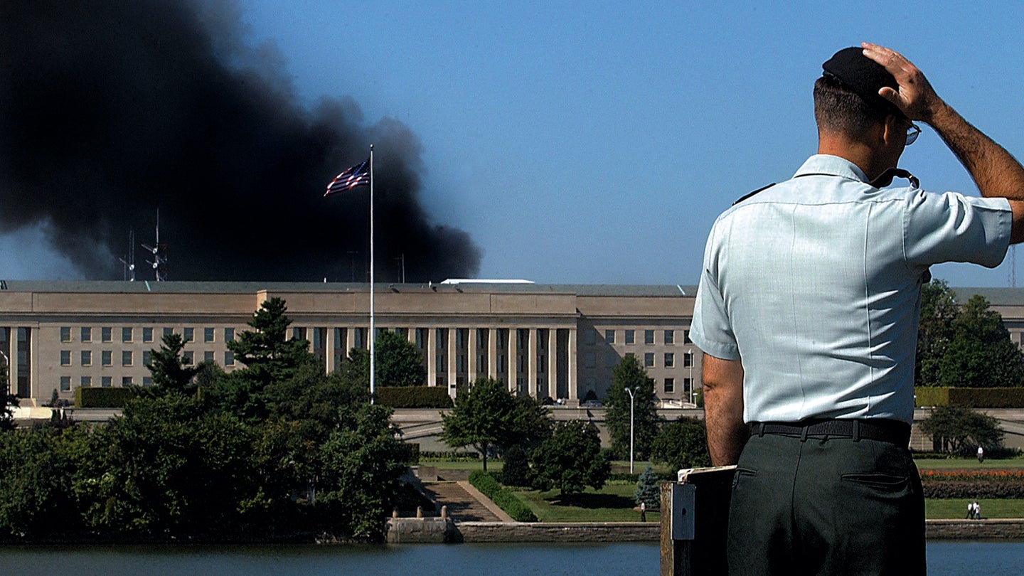 A Pentagon official stands across the Pentagon from which smoke is billowing following on Sept. 11, 2001. (Olivier Douliery/AFP via Getty Images)
