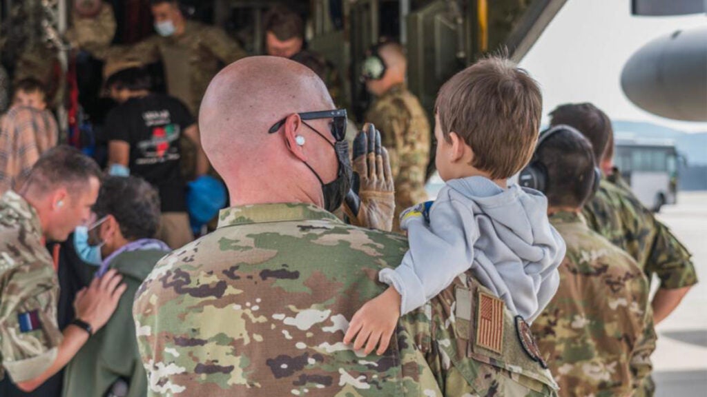 A U.S. Air Force Airman carries an evacuee child onto a C-130 Hercules aircraft during Operation Allies Refuge at Ramstein Air Base, Germany, Sept. 7, 2021. NATO personnel are supporting Operation Allies Refuge by assisting the 521st Air Mobility Operations Wing with outbound processing. (U.S. Air Force photo by Tech. Sgt. Donald Barnec)