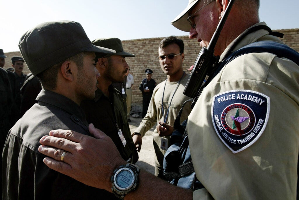 KABUL, AFGHANISTAN - SEPTEMBER 7: (US NEWS AND WORLD REPORT AND NEWSWEEK OUT) An Afghan police officer and instructor orders a class of basic patrol policemen to line up at a U.S. funded police training center September 7, 2004 in Kabul, Afghanistan. The Afghan police training course was initially organized by the German government and OSCE, but the U.S. Department of Defense wanted an accelerated turn out of Afghan trainers and officers. Since May 2003, the Kabul training center has turned out 25,000 policemen and officers under a variety of two to eight week courses, refresher courses for instructors and installed seven regional training centers throughout Afghanistan. With the upcoming presidential elections slated for October 9, 2004, U.S. government officials felt more security could be beefed up with more local police rather than U.S. or European army soldiers. Dyncorp Company hires former police officers as trainers on an annual or contract basis. The instructors plan to graduate 38,000 policemen by the end of 2004 and 52,000 by the end of 2005. Afghan Border and Highway Police will also be put through the various centers. Seventy percent of the Afghan policemen passing through the training centers are illiterate or from a low level of education. The students in brown uniforms are from little to no education backgrounds and in their 4th day of the course. Dyncorp supplies personal bodyguards and security for interim Afghan President Hamid Karzai. Dyncorp is made up of former U.S. Special Forces soldiers, European soldiers and police officers. Private security companies have become targets for Islamic militants in Afghanistan and in Iraq. A suicide bomber detonated a car bomb outside of the Dyncorp head office in Kabul, August 29, 2004, killing 6 people including three Americans, two Nepalis and one Afghan child. (Photo by Robert Nickelsberg/Getty Images)
