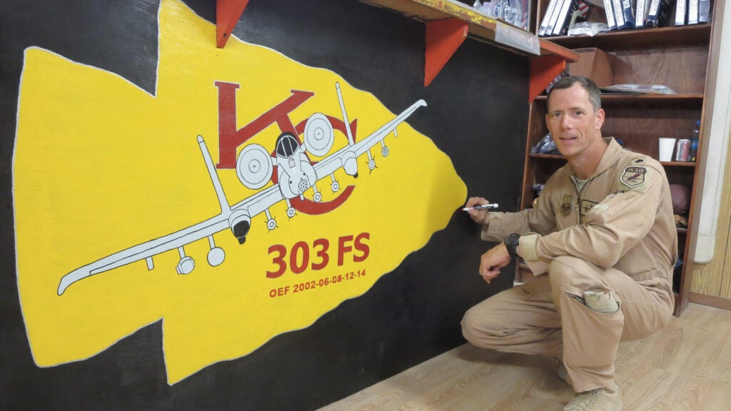 Lt. Col. John Marks smiles in front of his 303rd Fighter Squadron artwork at Bagram Air Base, Afghanistan, during Operation Enduring Freedom in 2014. The 303rd Fighter Squadron is attached to the 442d Fighter Wing, a Reserve wing located at Whiteman Air Force Base, Mo. (Photo courtesy of Lt. Col. John Marks)