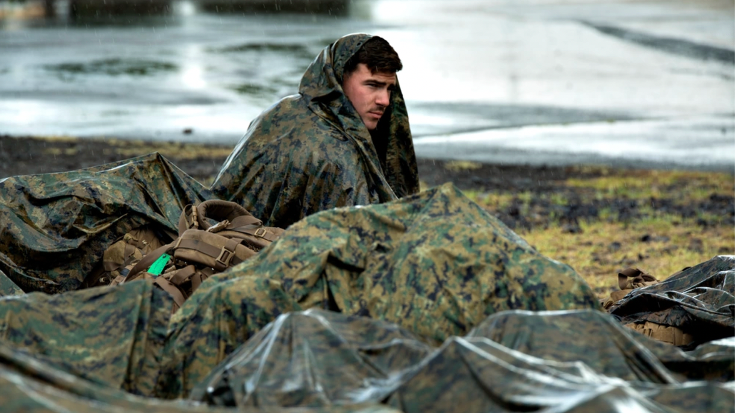 U.S. Marine Lance Cpl. William Ring keeps dry from the rain at Pohakuloa Training Area, Hawaii, July 15, 2016. (U.S. Marine Corps photo by Cpl. Isaac Ibarra) 
