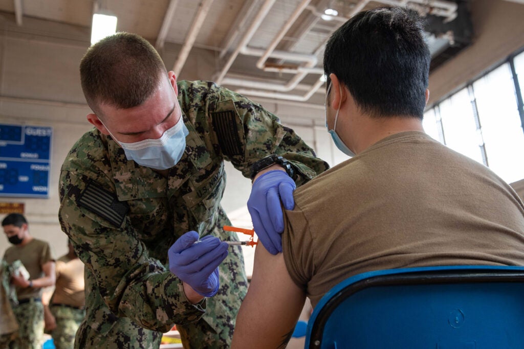 Hospital Corpsman 3rd Class Joseph Casassa, assigned to USS Gerald R. Ford’s (CVN 78) dental department, administers a COVID-19 vaccine to Logistics Specialist Seaman Rix Zhang, from Shen Yang, China, assigned to USS Gerald R. Ford’s (CVN 78) supply department, at the McCormick Gym onboard Naval Station Norfolk, April 8, 2021. (U.S. Navy photo by Mass Communication Specialist Seaman Jackson Adkins)