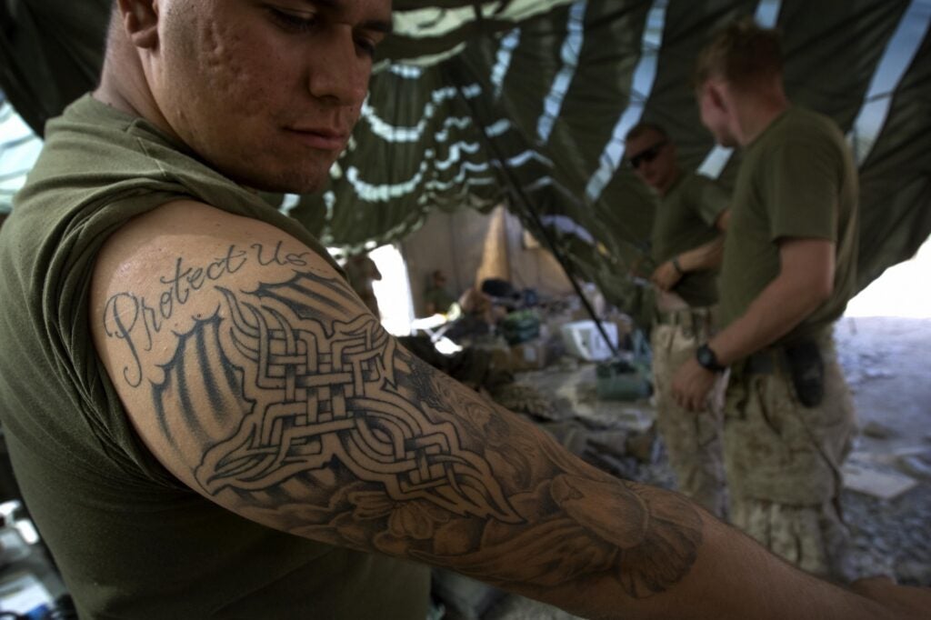 A US Marine from 2nd Marine Division MP Company shows off his tattoo that reads "Protect Us" at his forward operating base in Farah Province, southern Afghanistan, on September 27, 2009.  The top commander of US and NATO forces in Afghanistan has asked for 30,000-40,000 more troops to fight Islamist insurgents, Republican Senator John McCain said on today.  AFP PHOTO/DAVID FURST (Photo credit should read DAVID FURST/AFP via Getty Images)