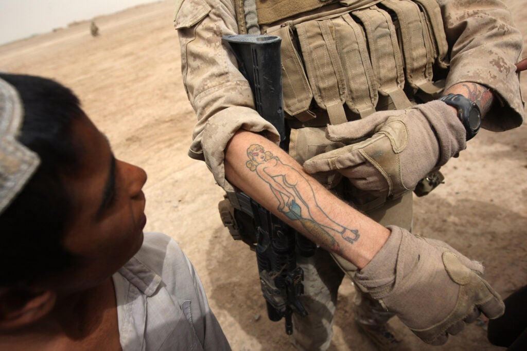 KIRTA, AFGHANISTAN - MARCH 23:  A U.S. Marine shows off a tattoo to a local boy while patrolling on March 23, 2009 in the village of Kirta, in remote southwest Afghanistan. Marines from the 3rd Battalion, 8th Marine Regiment met with local residents whom they rely on for information to help thwart Taliban attacks on U.S. troops.  (Photo by John Moore/Getty Images)