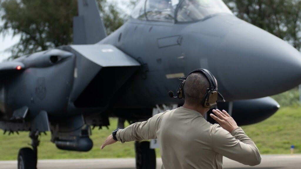 A U.S. Air Force Airman from the 389th Fighter Squadron directs an F-15E Strike Eagle at Tinian International Airport, July 27, 2021. (Airman 1st Class Andrea Rozoto/U.S. Air Force)